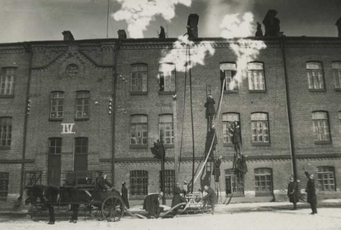 Gaisrininkai gesina gaisrą dideliame mūriniame name. Fotografija. Autorius, vieta ir laikotarpis nenustatyti. Lietuvos centrinis valstybės archyvas, P-13302